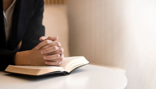 woman praying on holy bible in the morning.teenager woman hand with Bible praying,Hands folded in prayer on a Holy Bible in church concept for faith, spirituality and religion