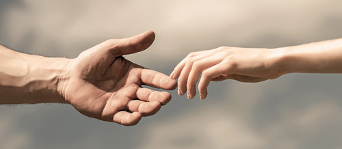 Hands of man and woman on blue sky background. Giving a helping hand. Lending a helping hand. Solidarity, compassion, and charity, rescue.